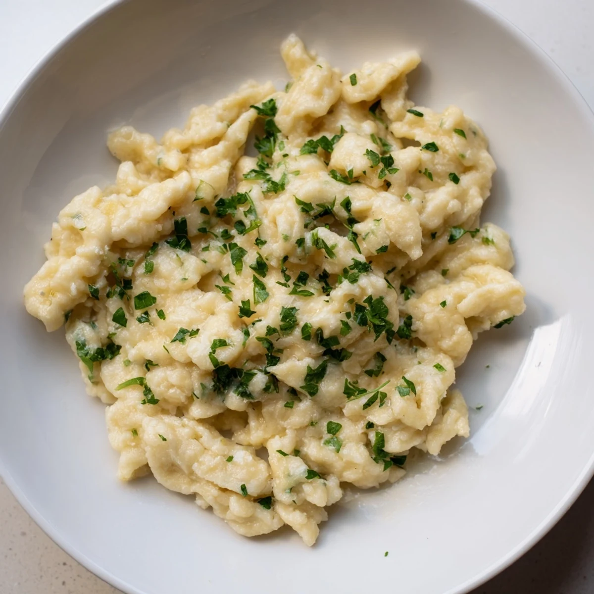 Fluffy spaetzle noodles, swimming in a glistening pot of boiling water, preparing for a delicious meal.