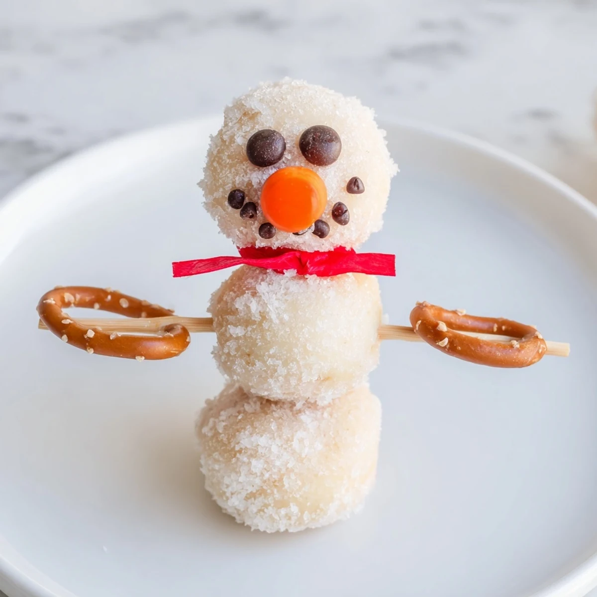 Mini Donut Snowman Stack: charming no-bake dessert featuring mini donuts stacked high with candy eyes and pretzels.