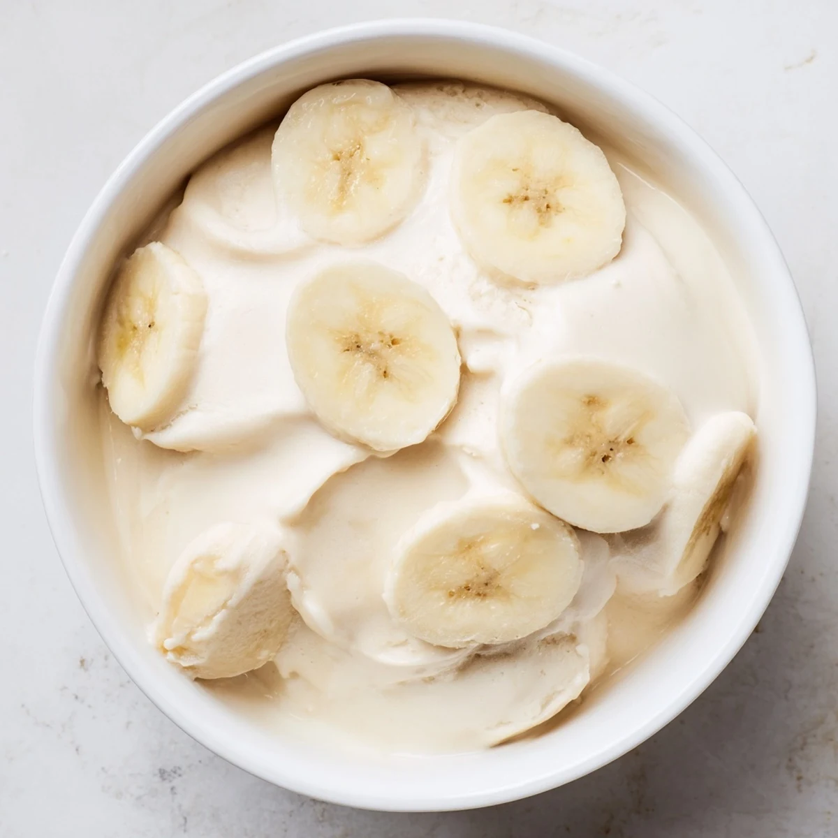 Köstliches 2-Zutaten-Bananeneis, mit gefrorenen Bananenscheiben und Milch, perfekt für eine gesunde Nascherei.