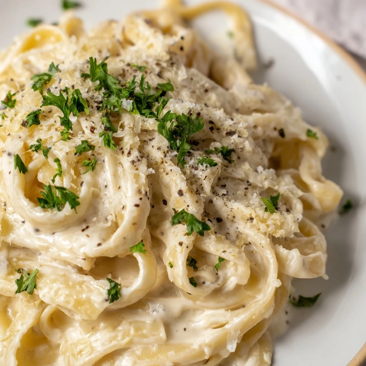 Creamy cottage cheese Alfredo sauce coats pasta with fresh parsley garnish, ready to serve.