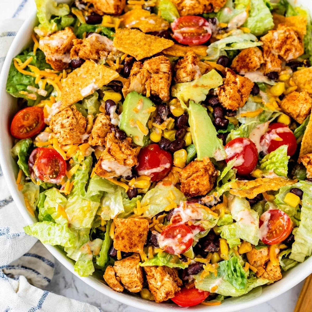 Saftige Hähnchenbrustwürfel auf einer bunten Schüssel aus gemischtem Salat, schwarzen Bohnen, Mais und Avocado für ein Protein-reiches Mittagessen.