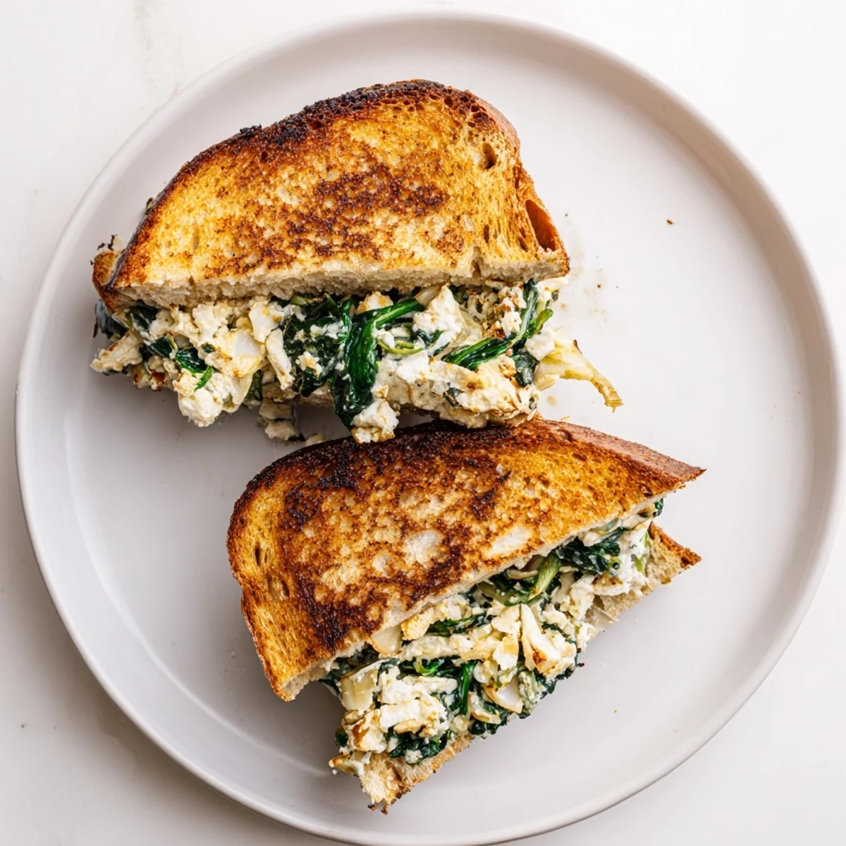 Frisch zubereitetes Feta & Spinach Stuffed Grilled Cheese, serviert neben einer Tasse Tomatensuppe für die Mittagspause.