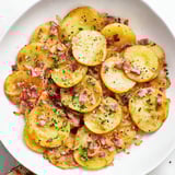 Savory bacon bits and sweet onions sizzle alongside the Simple Fried Potatoes recipe.