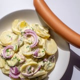 Hearty German Potato Salad with Sausages, showcasing tender potatoes and perfectly grilled sausage.