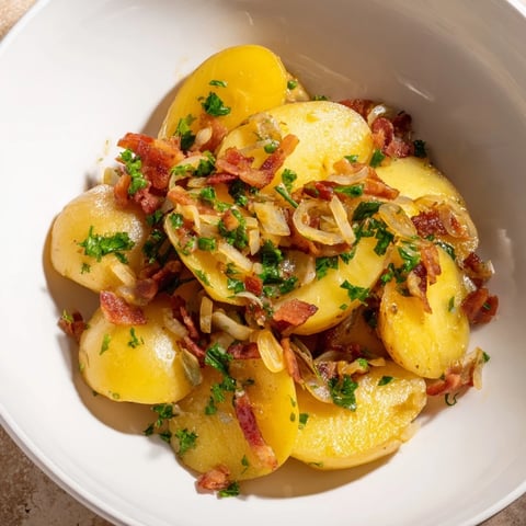 Steaming warm German potato salad, glistening with a savory vinegar dressing and crispy bacon.