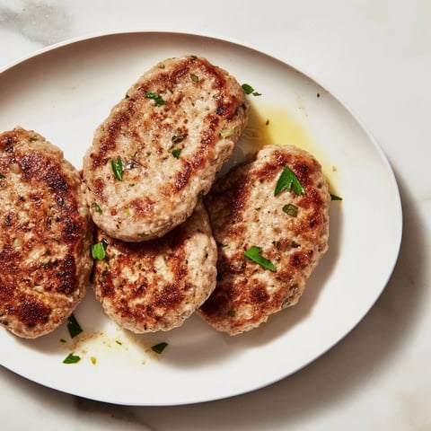 Juicy, browned Frikadellen, a German meatball dish, sizzling in a pan with flavorful spices.