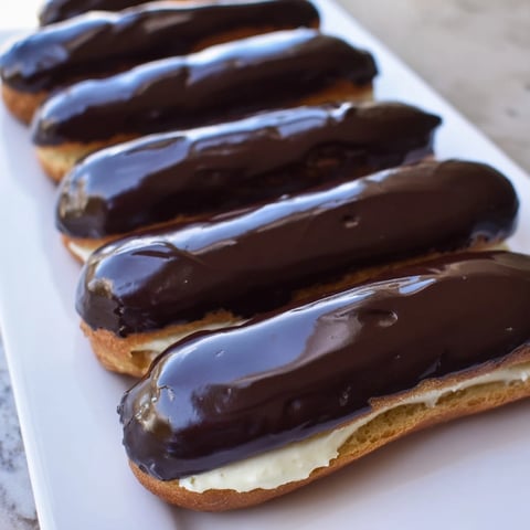 Mini Chocolate Éclairs in a row, a close-up of the French dessert with glazed chocolate tops.