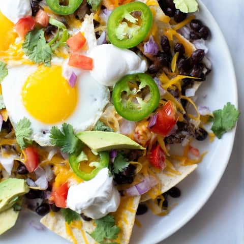 Melted cheese and perfectly cooked eggs top these flavorful Egg-Topped Breakfast Nachos, a delicious Tex-Mex treat.