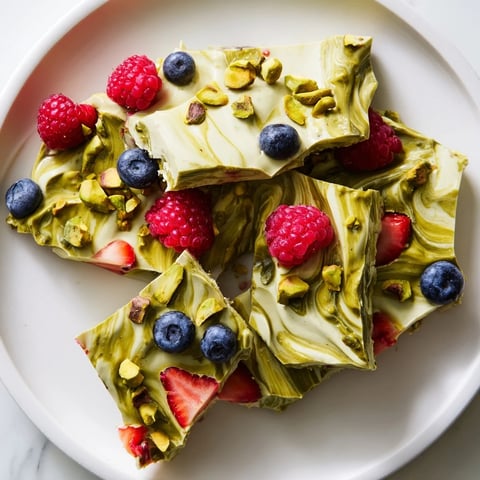 Frozen yogurt bark swirled with vibrant berries and pistachios, a refreshing, beautiful dessert.