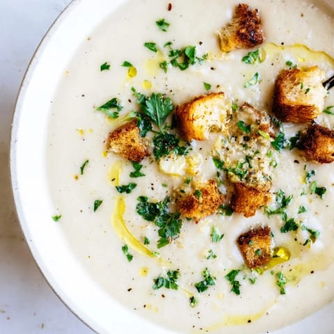 A steaming bowl of creamy garlic potato soup, perfect for a cozy, vegan dinner.