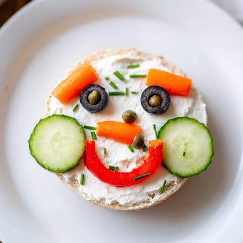Festive snowman mini bagel sandwiches, a close-up shows the cream cheese and colorful veggie faces.