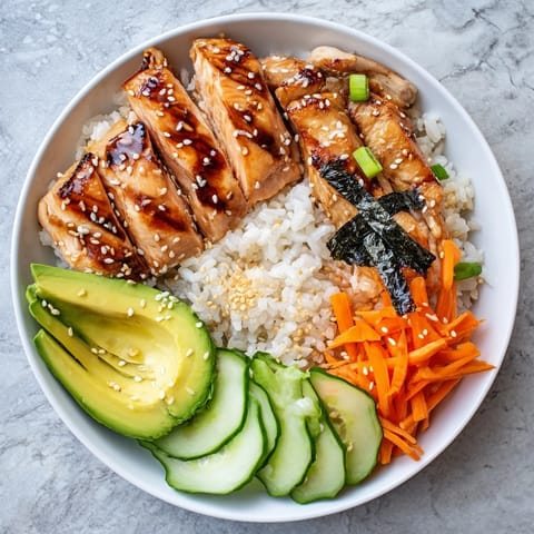 A beautifully arranged Japanese-Style Salmon & Chicken Rice Bowl, showcasing colorful fresh vegetables on top.
