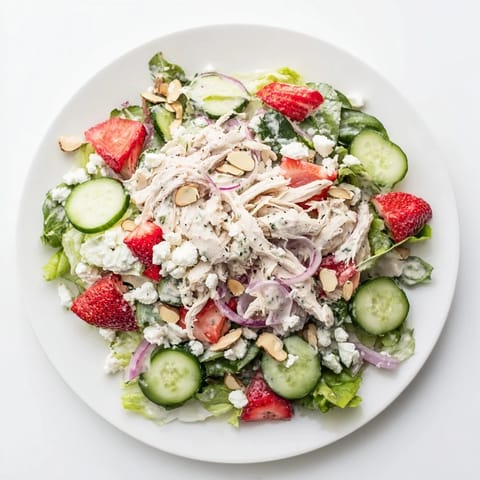 Ein frischer Sommer-Salat mit zartem Hühnchen, süßen Erdbeeren und knusprigen Mandeln, verfeinert mit einer cremigen Mohnsamen-Dressing.