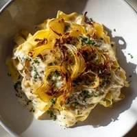 Goldene, karamelisierte Zwiebeln bedecken die One-Pot French Onion Pasta, dampfend im Topf, bereit zum Servieren.